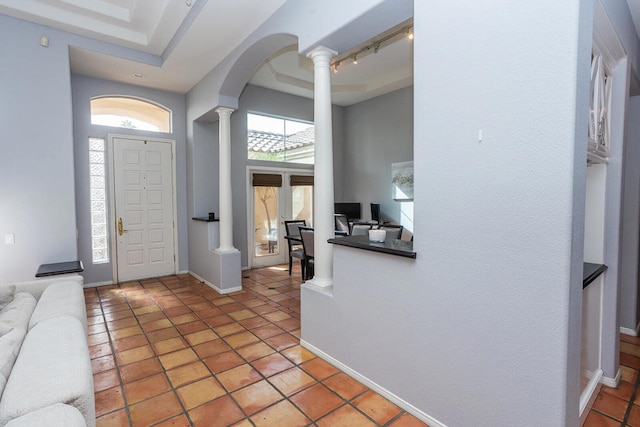 tiled foyer entrance with rail lighting, a raised ceiling, and plenty of natural light