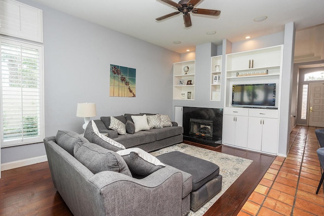 living room with a healthy amount of sunlight, built in shelves, ceiling fan, and dark tile patterned flooring