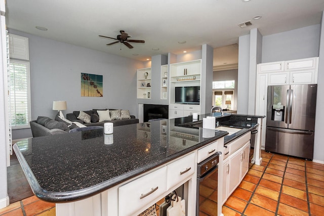 kitchen with plenty of natural light, stainless steel refrigerator with ice dispenser, white cabinetry, and a kitchen island with sink