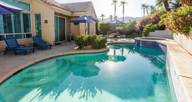 view of pool with a mountain view, a patio, and an in ground hot tub