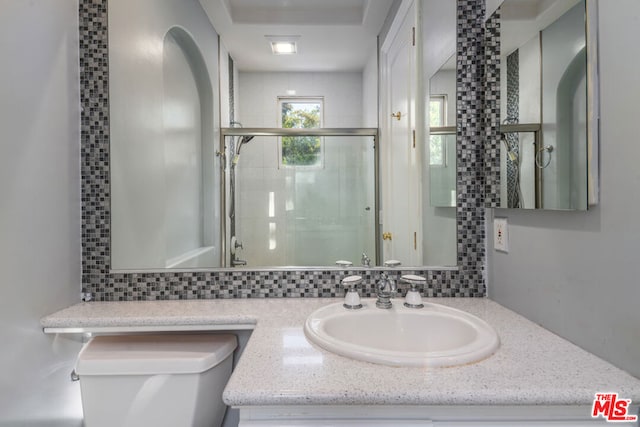 bathroom featuring vanity, walk in shower, tasteful backsplash, and toilet