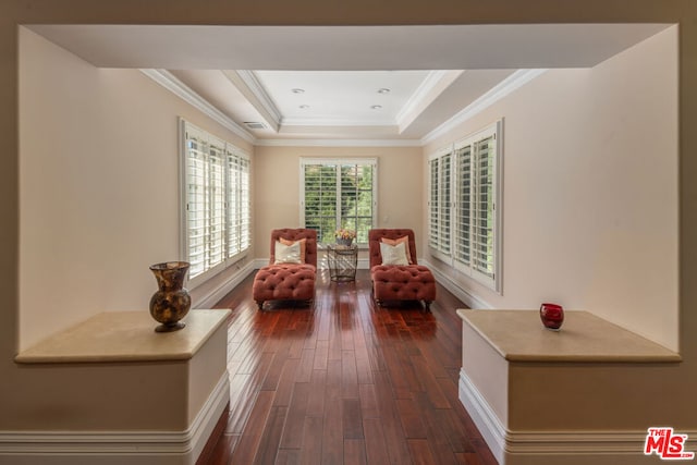 living area with ornamental molding, a tray ceiling, and dark wood-type flooring