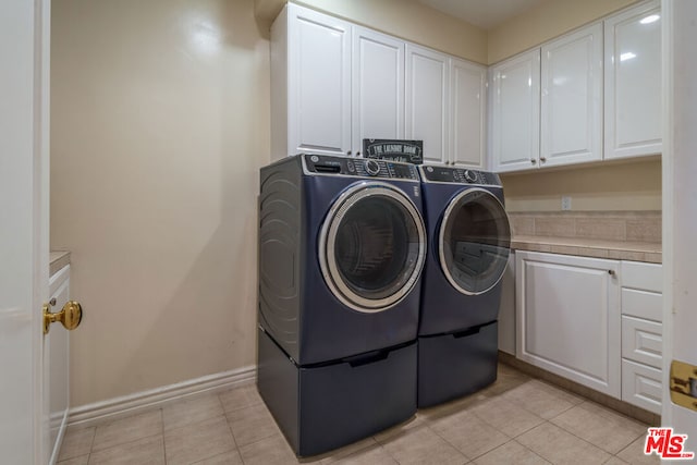 laundry room with light tile patterned floors, independent washer and dryer, and cabinets