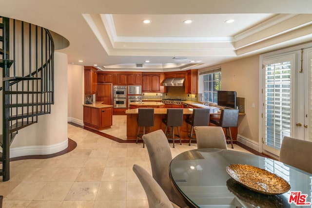 dining room with a raised ceiling, light tile patterned flooring, crown molding, and sink