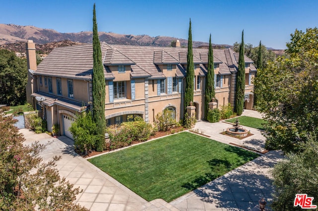 view of property with a mountain view, a front lawn, and a garage