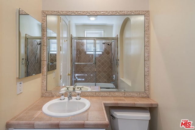 full bathroom with enclosed tub / shower combo, vanity, and toilet