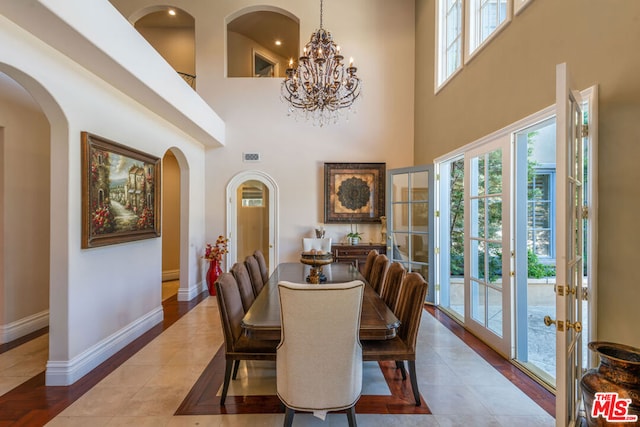 dining space with an inviting chandelier, a high ceiling, and french doors