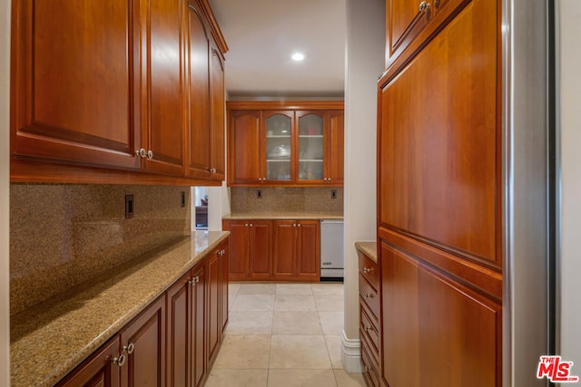 kitchen with light stone countertops, backsplash, light tile patterned floors, and stainless steel dishwasher