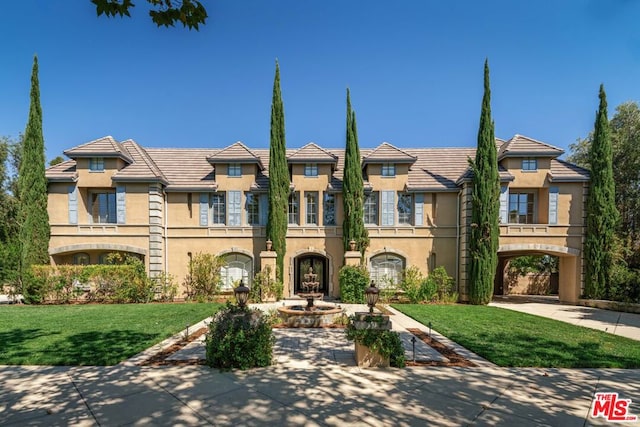 townhome / multi-family property featuring a balcony and a front lawn