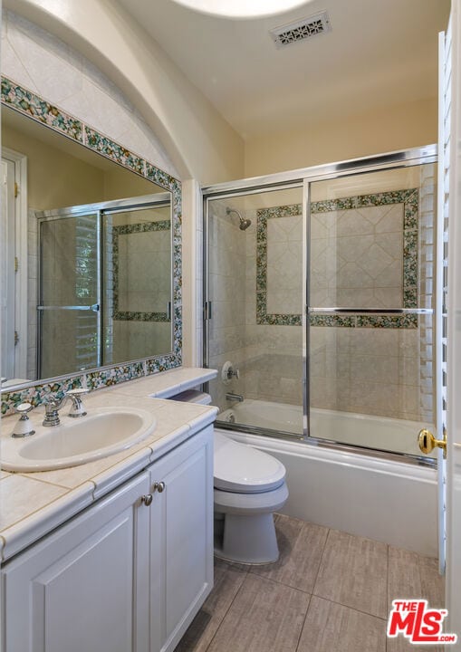 full bathroom featuring enclosed tub / shower combo, vanity, and toilet