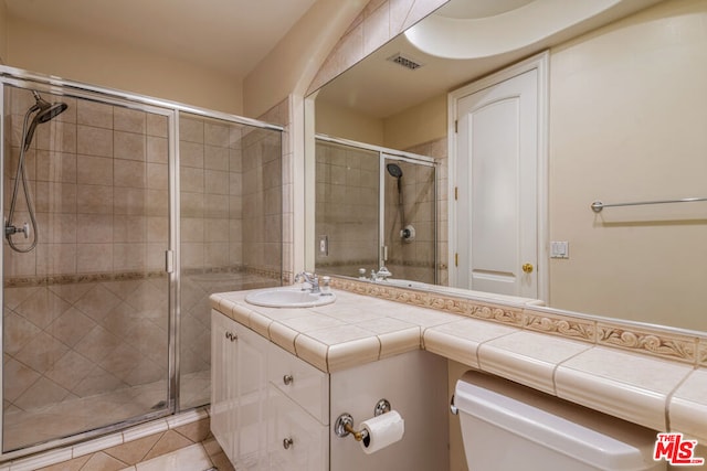 bathroom with vanity, tile patterned flooring, toilet, and an enclosed shower