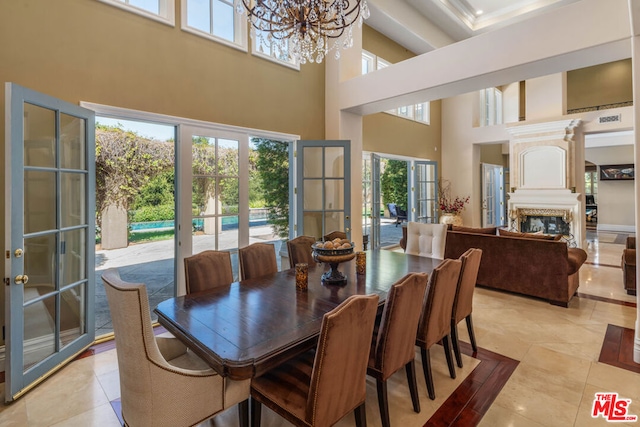 dining room with light tile patterned flooring, a towering ceiling, french doors, and a notable chandelier