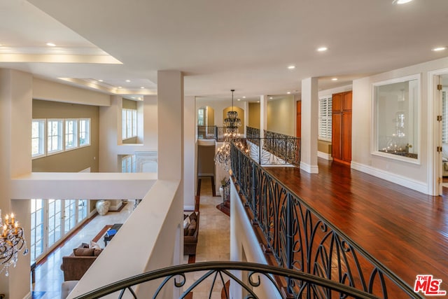 corridor featuring hardwood / wood-style flooring, crown molding, and a notable chandelier