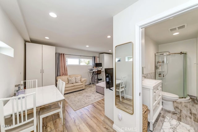 bathroom with hardwood / wood-style floors, vanity, toilet, and walk in shower