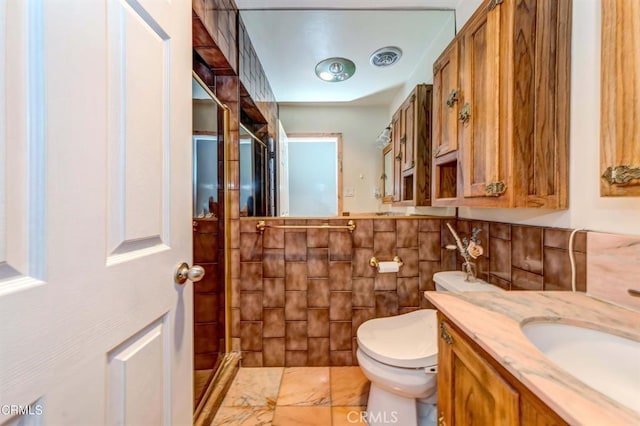 bathroom with vanity, toilet, and tile walls