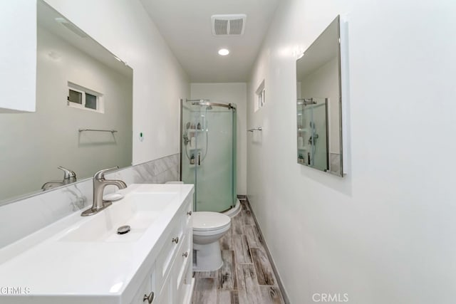 bathroom with wood-type flooring, vanity, toilet, and walk in shower