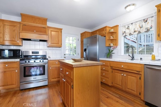 kitchen featuring light hardwood / wood-style floors, backsplash, a center island, and stainless steel appliances