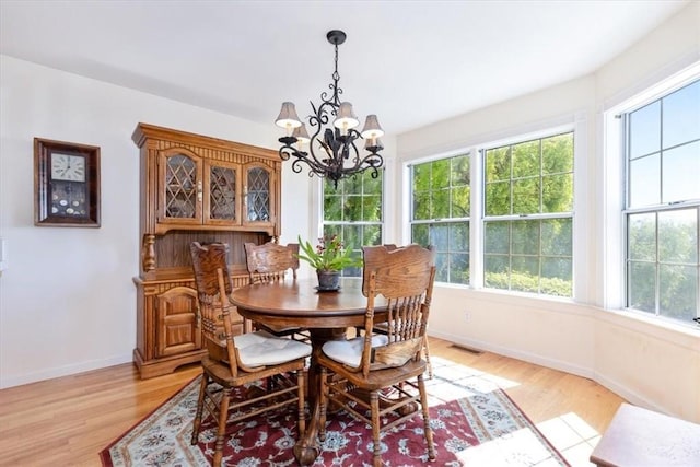 dining area with light wood-type flooring and a chandelier