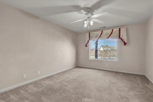 carpeted spare room featuring ceiling fan