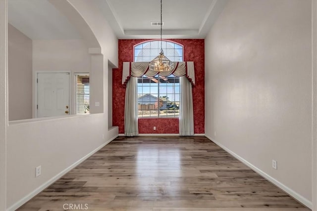 entrance foyer featuring hardwood / wood-style floors, a tray ceiling, and an inviting chandelier