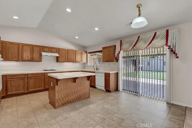 kitchen featuring decorative light fixtures, dishwasher, vaulted ceiling, a kitchen island, and sink