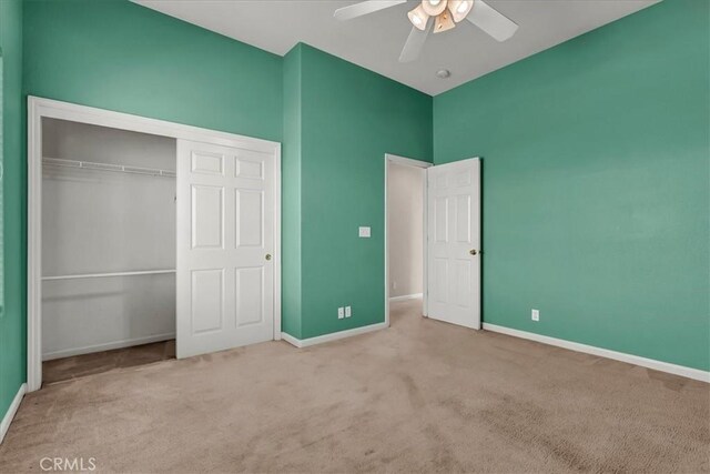 unfurnished bedroom featuring ceiling fan, a closet, and light colored carpet