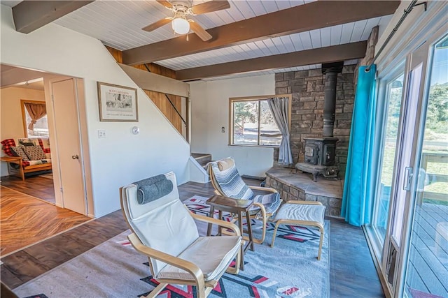 interior space featuring beam ceiling, a wood stove, ceiling fan, and wood-type flooring