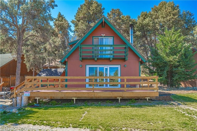 back of house with a yard, a balcony, and a wooden deck