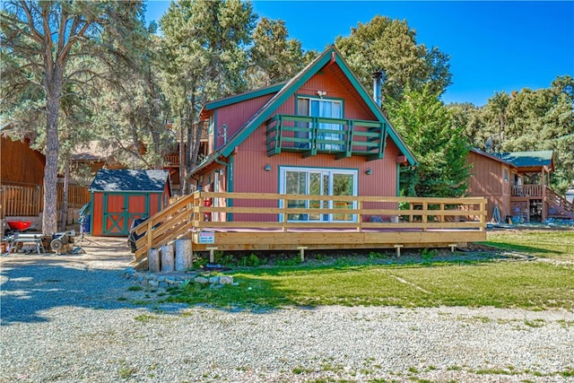 back of property featuring a lawn, a balcony, a deck, and a storage shed