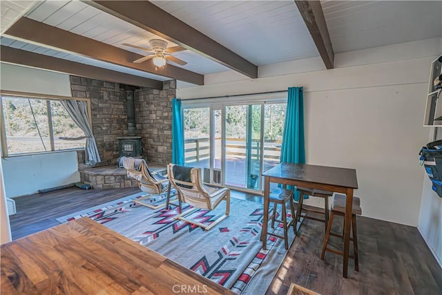 living room featuring a wood stove, ceiling fan, plenty of natural light, and dark wood-type flooring