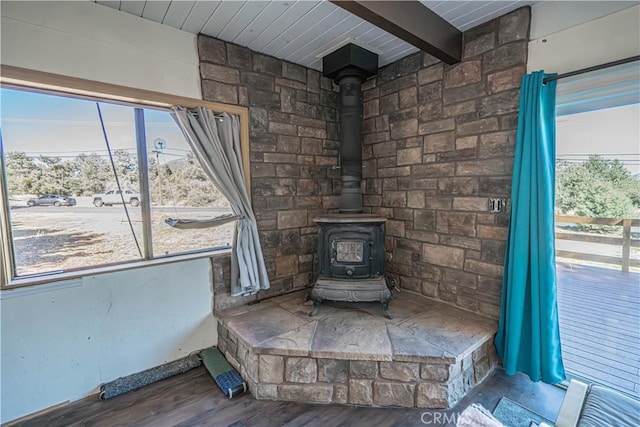 interior details with hardwood / wood-style floors, beam ceiling, and a wood stove