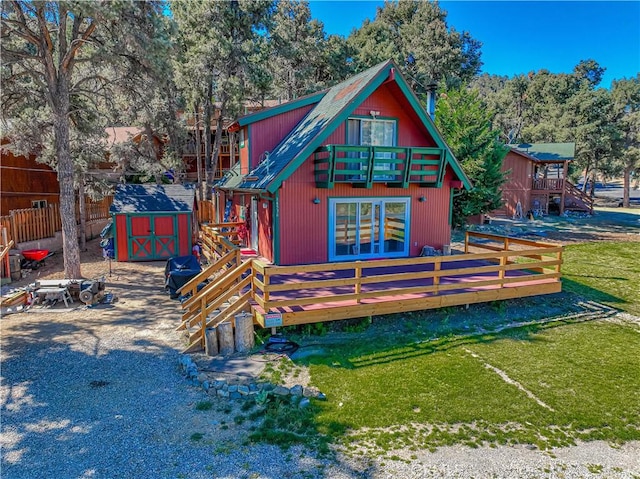 rear view of property with a wooden deck, a yard, a balcony, and a shed