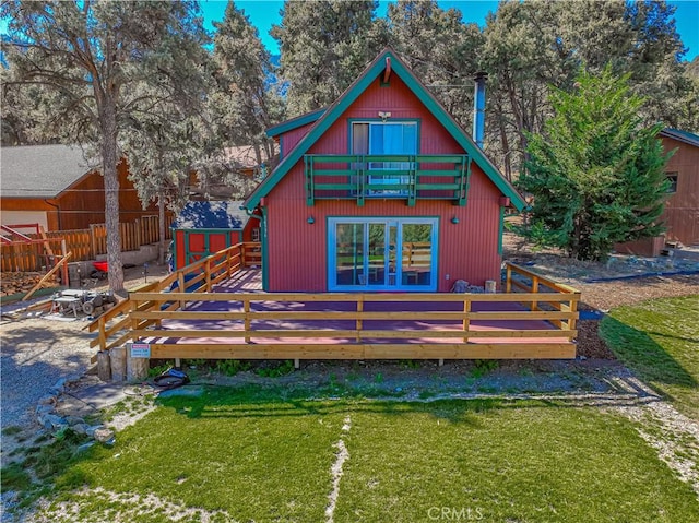 back of property featuring a lawn, a balcony, and a wooden deck