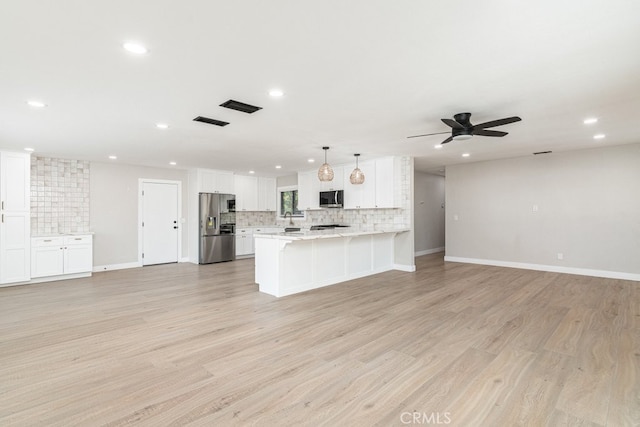 kitchen with white cabinetry, stainless steel appliances, kitchen peninsula, pendant lighting, and light hardwood / wood-style floors