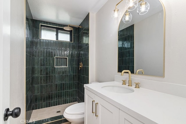 bathroom featuring a tile shower, vanity, a textured ceiling, and toilet