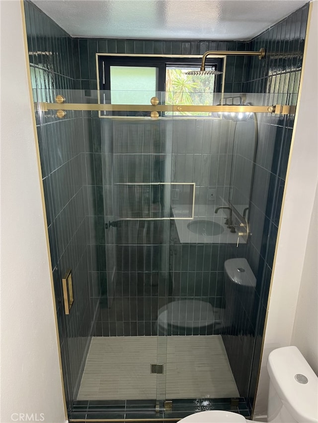 bathroom featuring a textured ceiling, toilet, and an enclosed shower