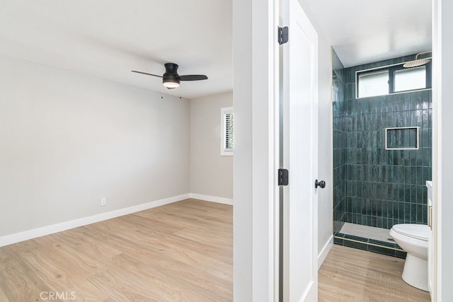 bathroom with tiled shower, ceiling fan, hardwood / wood-style floors, and toilet