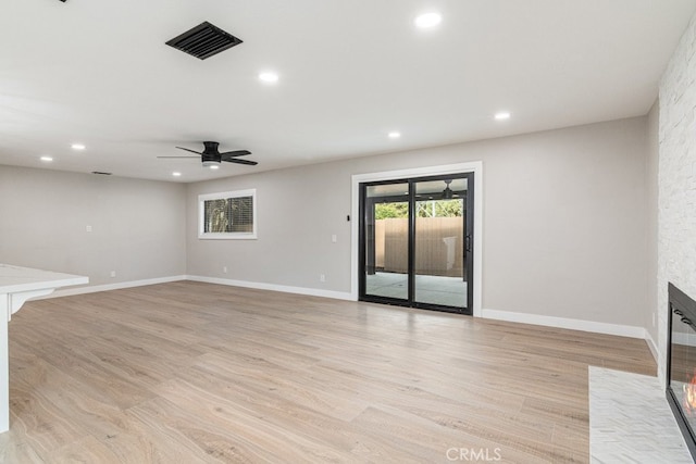 unfurnished living room featuring ceiling fan, a fireplace, and light hardwood / wood-style flooring