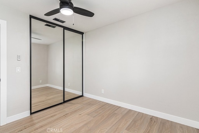 unfurnished bedroom with a closet, light hardwood / wood-style flooring, and ceiling fan