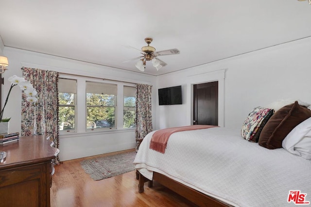 bedroom featuring light wood-type flooring, ceiling fan, and crown molding