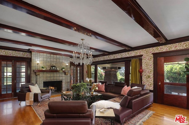 living room featuring light hardwood / wood-style flooring, an inviting chandelier, beamed ceiling, and a fireplace