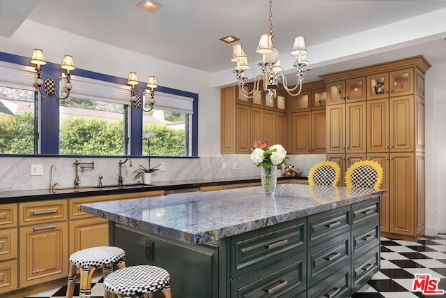 kitchen with backsplash, dark stone countertops, a kitchen island, and a chandelier