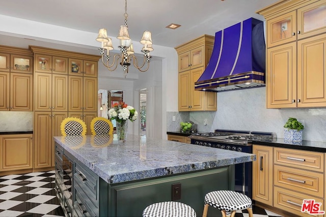 kitchen featuring dark stone counters, a center island, custom exhaust hood, and a notable chandelier