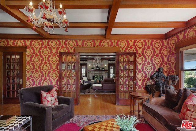 living room featuring wood-type flooring, a notable chandelier, beam ceiling, and coffered ceiling