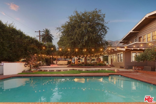 pool at dusk with a patio area