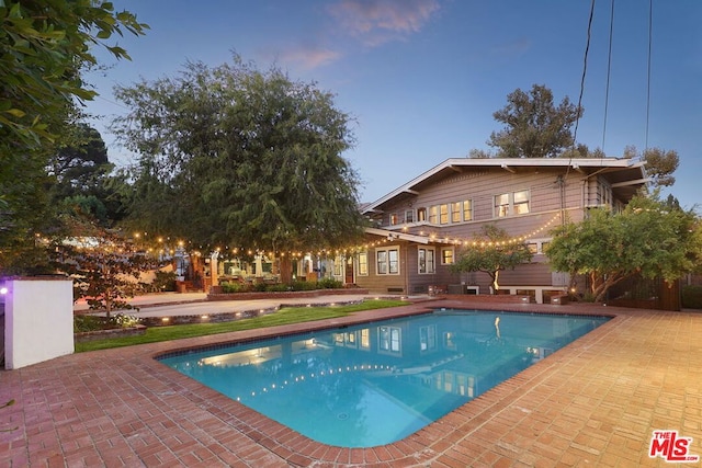 pool at dusk with a patio