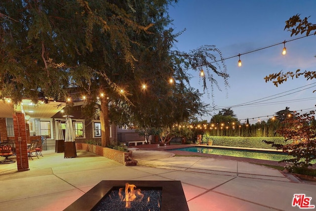 patio terrace at dusk featuring a fire pit