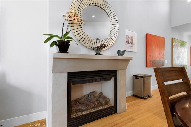 interior details featuring a glass covered fireplace, wood finished floors, and baseboards