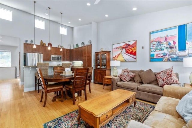 living room with light hardwood / wood-style floors and a towering ceiling