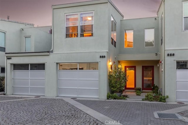 view of front of house with an attached garage, decorative driveway, and stucco siding